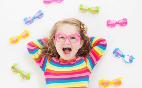 Bambina sorridente circondata da occhiali da sole Cimmino Lab