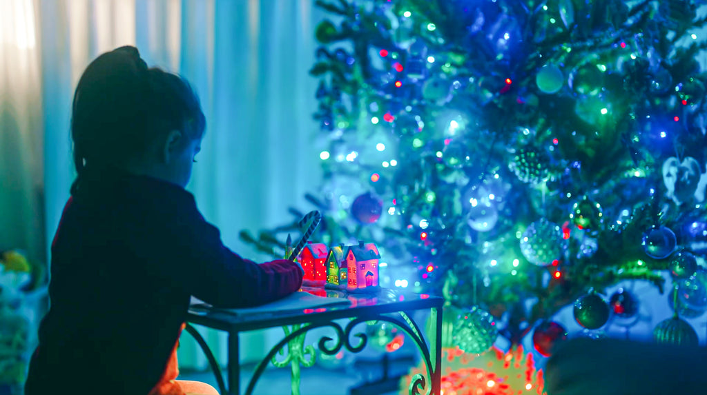 Bambina che scrive lettera di pace per Natale. Albero di Natale illuminato ed atmosfera magica